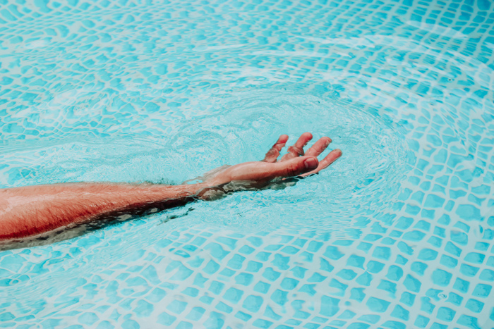 A persons hand spread out in water using orange and blue color scheme 