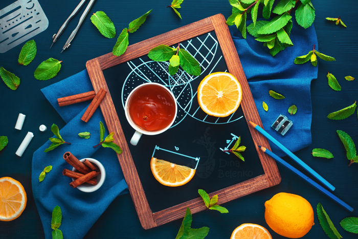 A blue and orange themed flat lay including oranges and teacups on a chalkboard